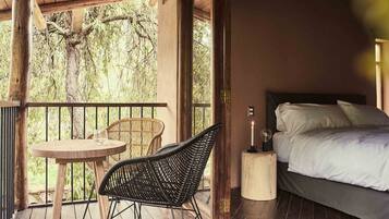 A bedroom with a bed, a nightstand, and a table with chairs on a balcony.