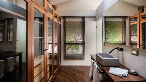 Une salle de bain moderne avec des portes coulissantes en bois, un grand miroir, un lavabo intégré et une fenêtre avec des stores.