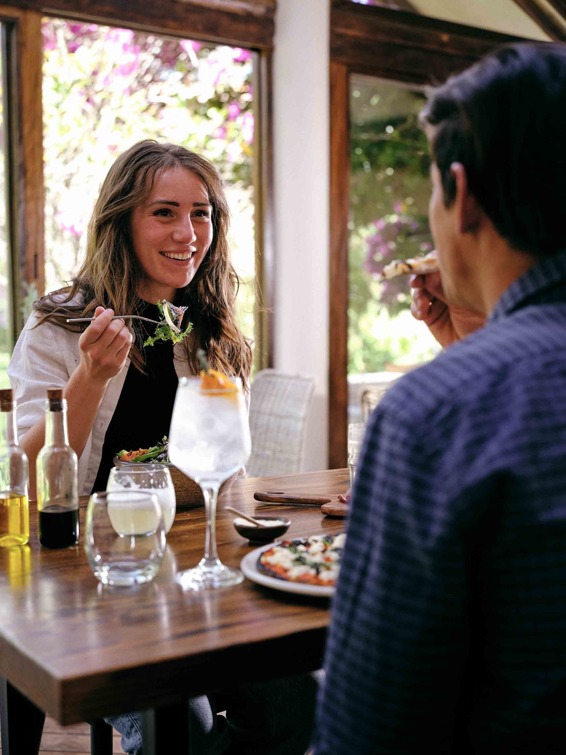 A dining table with a meal, a glass of water, and a bottle of olive oil.