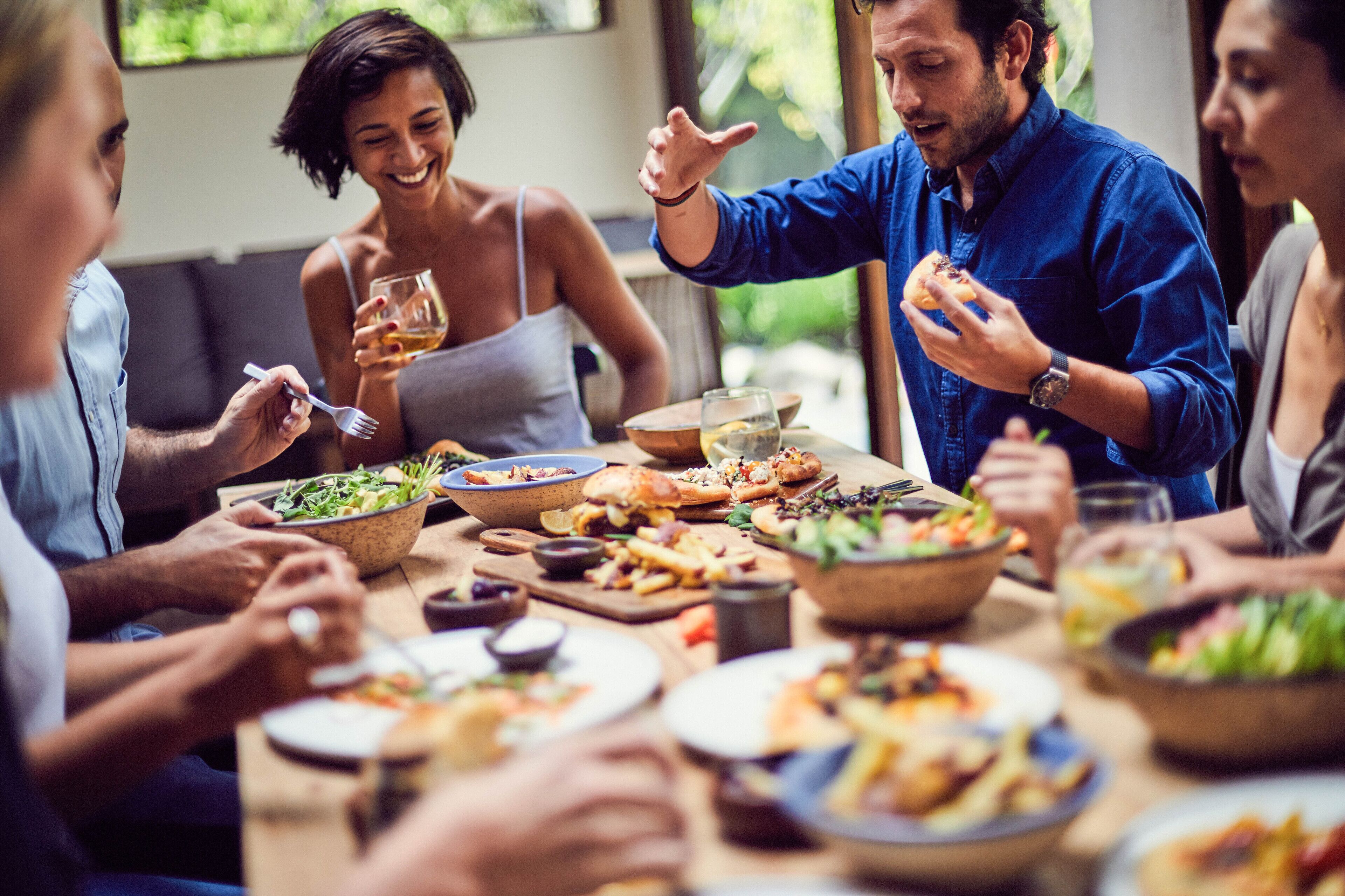 A group of people dining at a table with various dishes and drinks.
