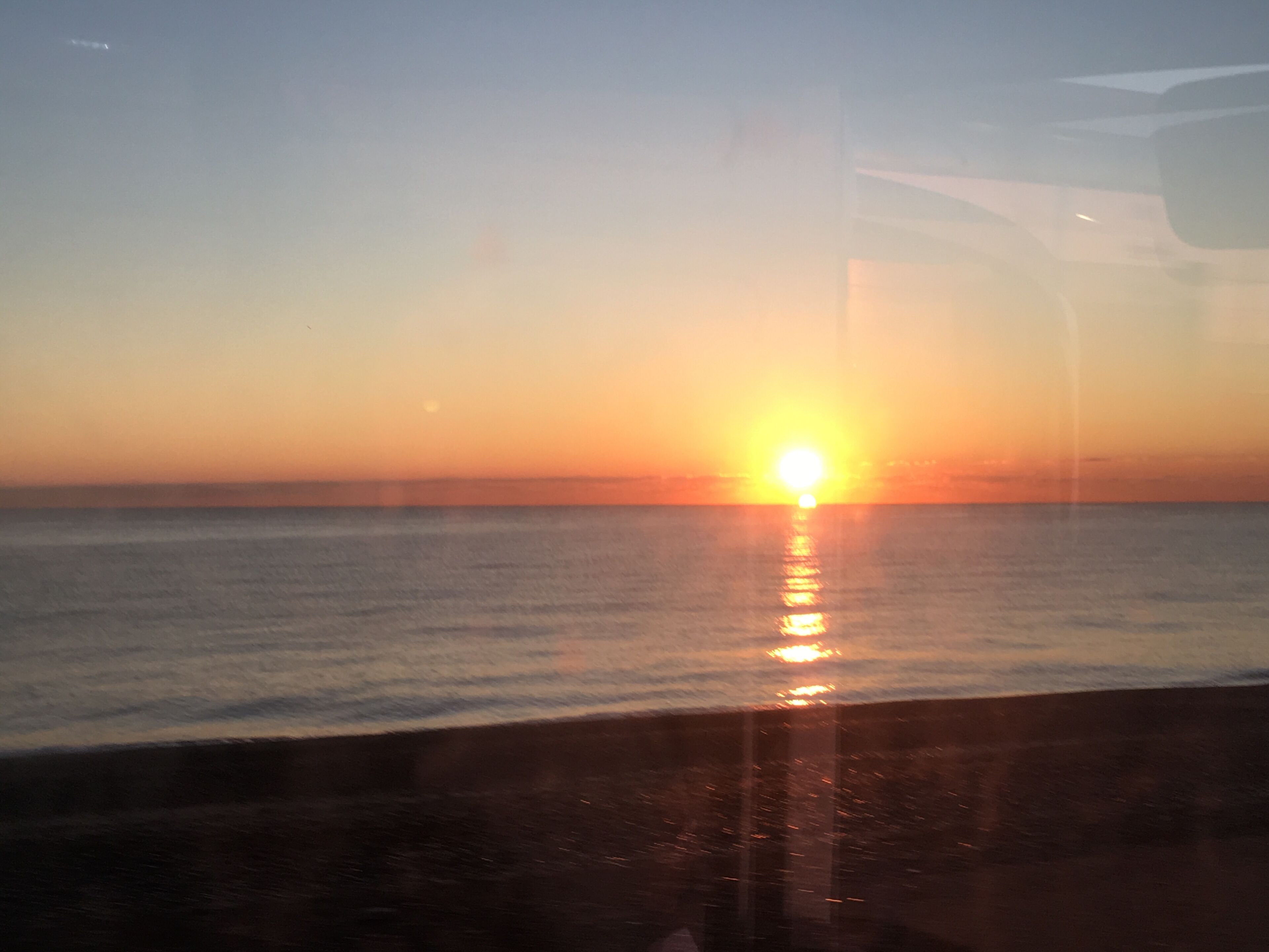Un atardecer sobre un mar tranquilo con horizonte despejado.