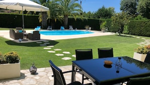 Un jardin avec une piscine, un espace salon extérieur et un coin repas.
