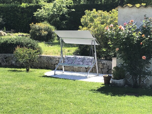 A garden with a swing set, a stone wall, and a variety of plants and flowers. - CHARMING FAMILY VILLA WITH SWIMMING POOL 15 MINUTES FROM THE SEA (Vence)