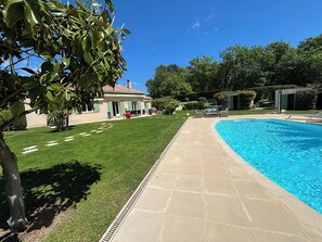 A swimming pool with a tiled deck, a lawn, and a building with a green door and shutters. - CHARMING FAMILY VILLA WITH SWIMMING POOL 15 MINUTES FROM THE SEA (Vence)
