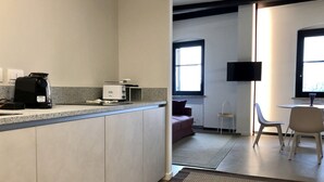 A modern kitchen with a coffee maker, microwave, and a small refrigerator. There is a window providing natural light and a flat-screen TV mounted on the wall. - Rivadige Suite 4 with beautiful view on the river (Verona)