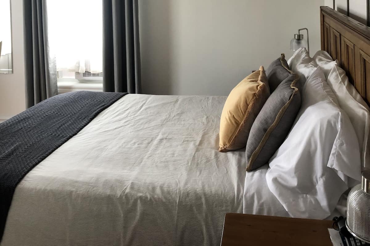 Un dormitorio con una cama grande, cabecera de madera y tres cuadros en la pared.