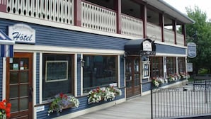 A hotel with a balcony, large windows, and flower boxes. - Auberge Knowlton (Lac-Brome)
