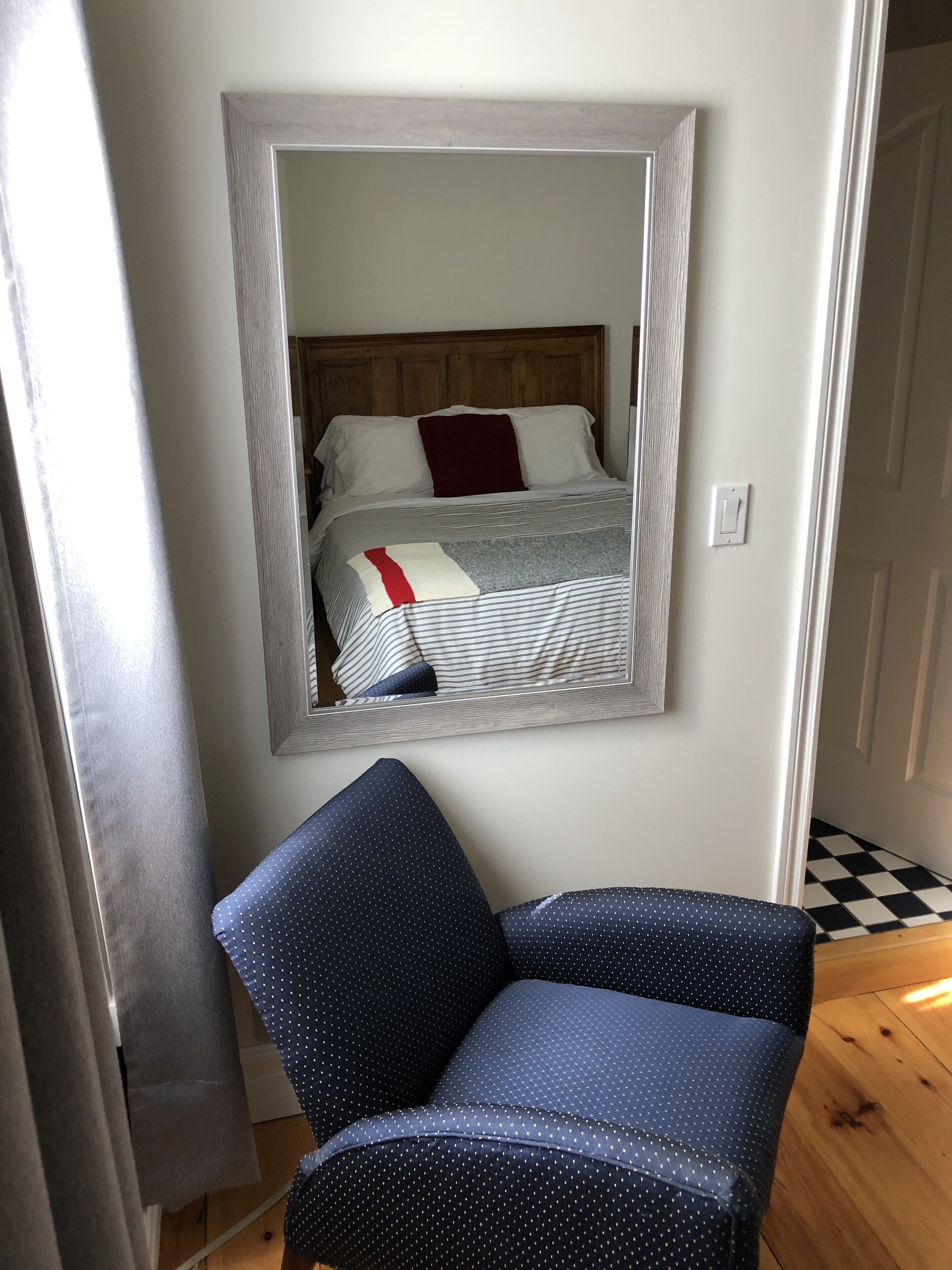 A room with a bed, a mirror, and a blue chair.