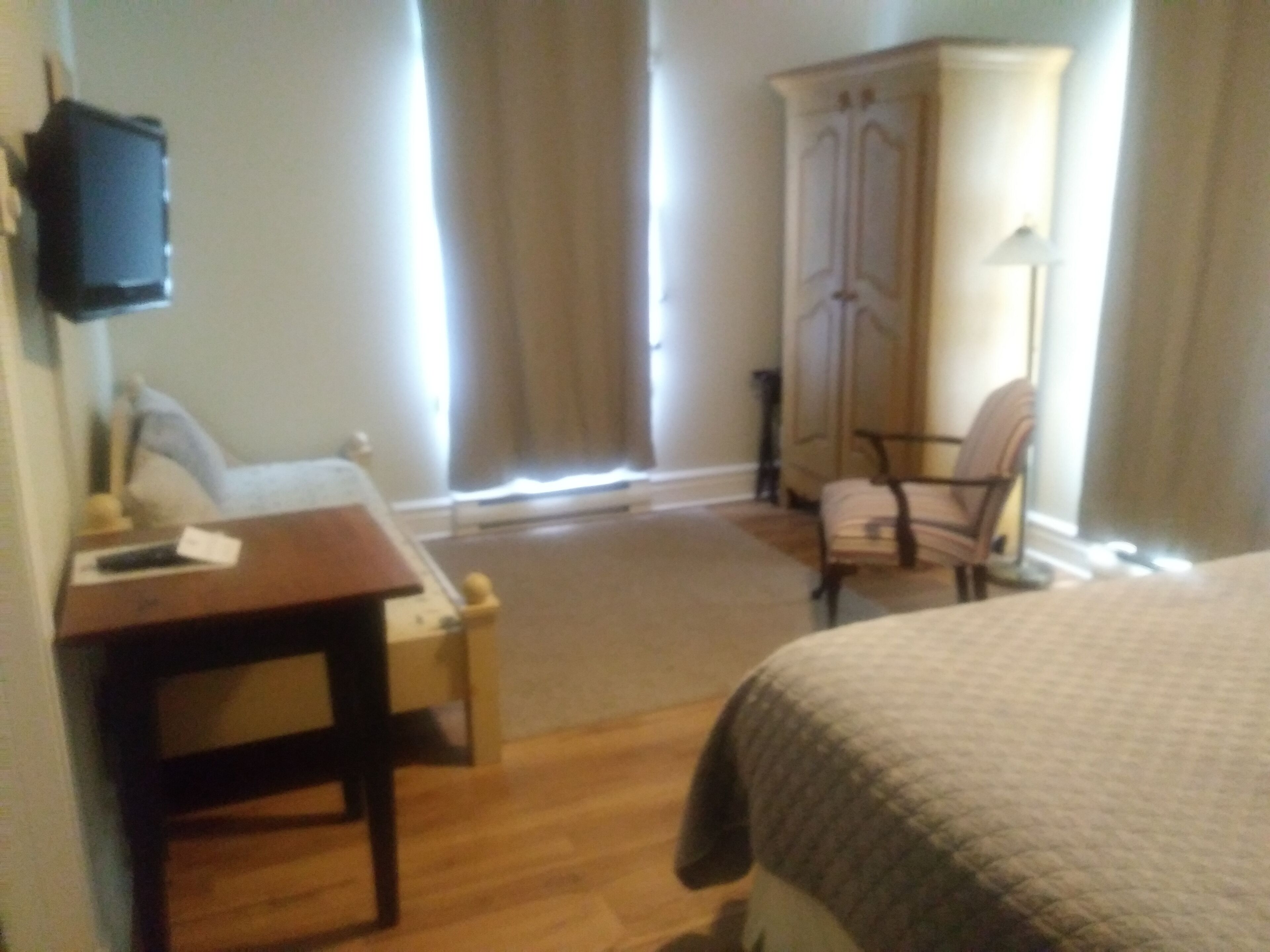 Une chambre d’hôtel équipée d’un lit, d’un bureau, d’une chaise, d’une armoire et d’un téléviseur fixé au mur.