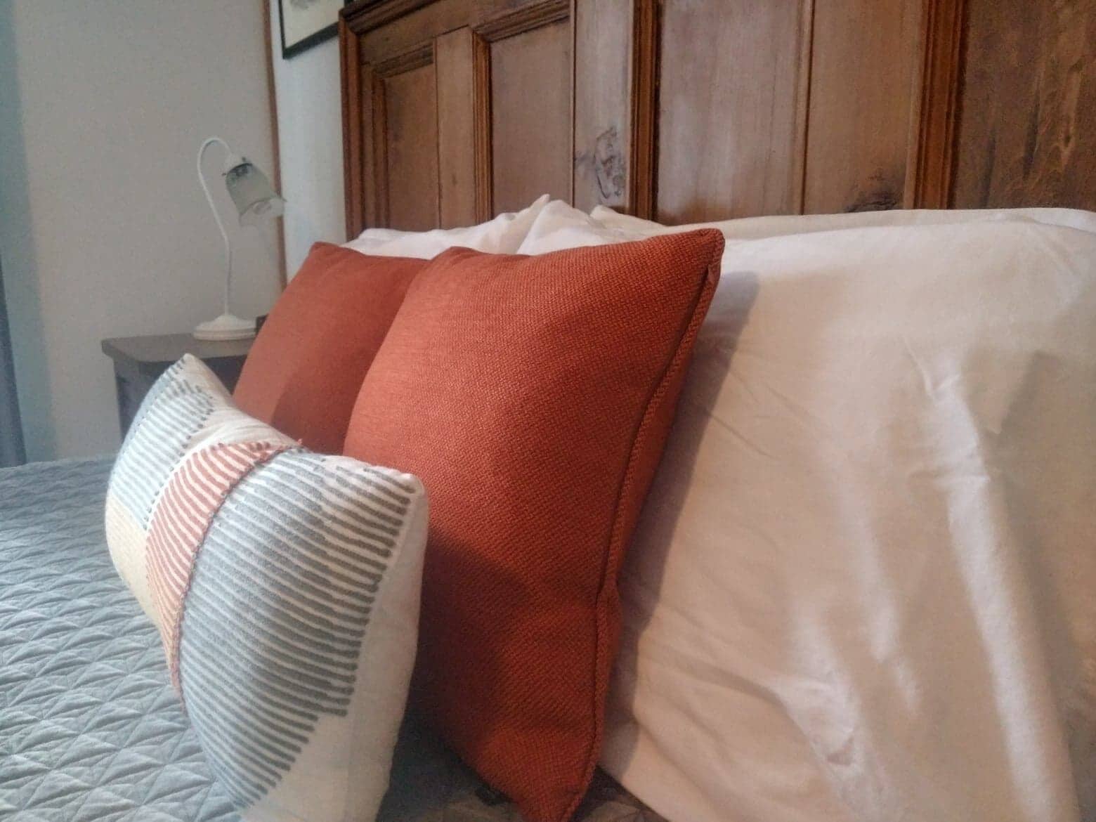 Una cama con una colcha acolchada y tres almohadas de diferentes colores.