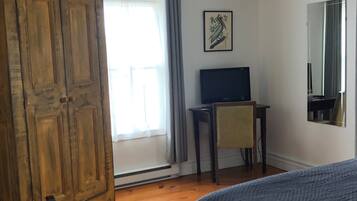 A bedroom with a bed, a desk, a chair, a wardrobe, and a ceiling fan.