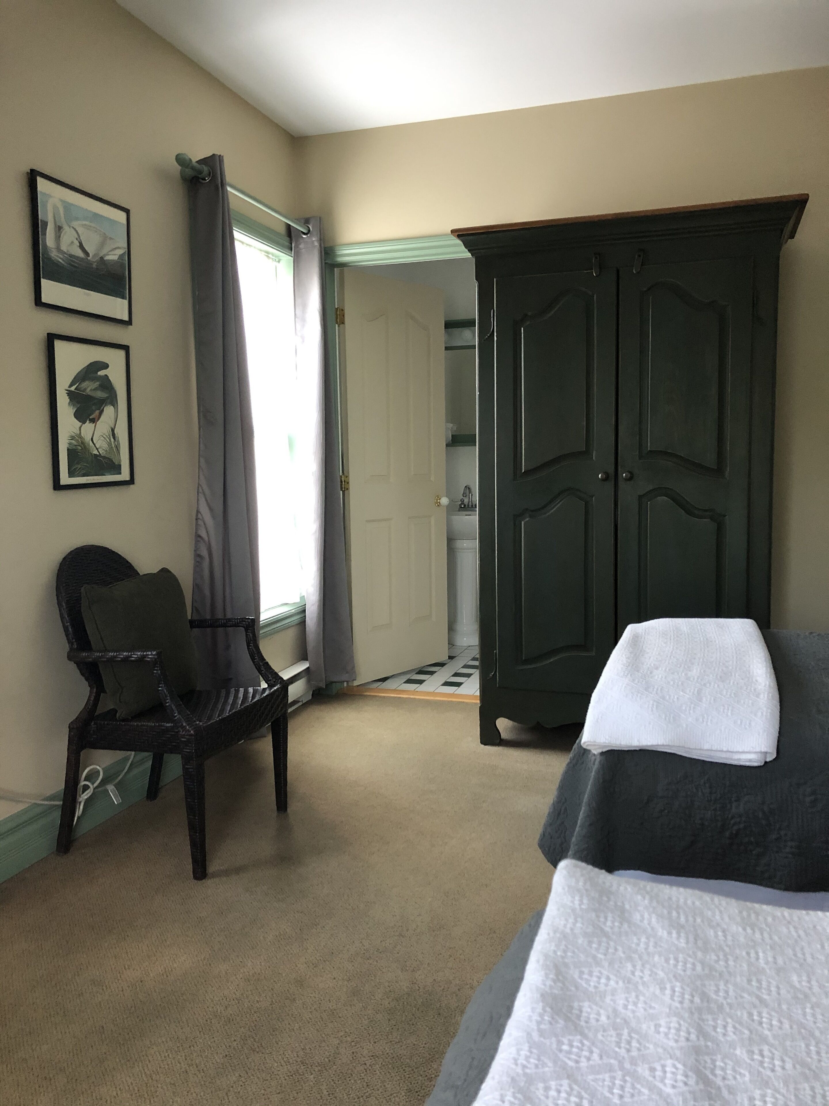 Un dormitorio con cama, una silla, un armario y una puerta que da al baño.