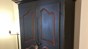 A dark wooden cabinet with two doors, a small tag on one door, and a lamp to the left. - Auberge Knowlton (Lac-Brome)
