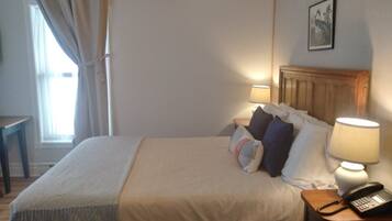 Une chambre d’hôtel avec un lit, des lampes de chevet, un téléphone et un tableau au mur.