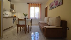 A modern kitchen with a dining area, a sofa, and a painting on the wall. - Apartment Kuftic - Relax Zone (Rovinj)