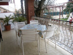 An outdoor patio with a table and chairs, a brick pillar, and a metal railing. - Apartment Kuftic - Relax Zone (Rovinj)