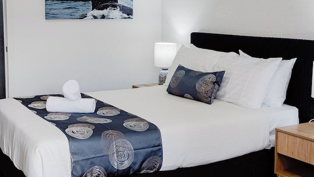 A hotel room with a bed, a nightstand, a lamp, and a wall-mounted picture of a whale. - The Caledonian Inn (Port Fairy)
