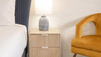 Une chambre d’hôtel avec un lit, une table de chevet avec une lampe et une chaise.