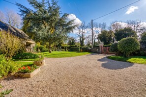 A gravel driveway leading to a house with a sloped roof, surrounded by a well-maintained garden with various plants and flowers. - Homerez - House in Pordic (Pordic)