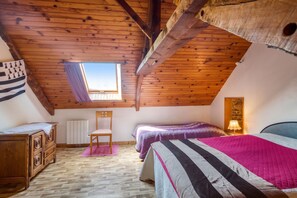 A cozy attic bedroom with a sloped ceiling, a window, a wooden dresser, a chair, and a bed with striped bedding. - Homerez - House in Pordic (Pordic)