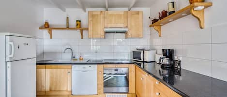 Una cocina moderna con armarios de madera, encimera negra, lavavajillas, microondas y cafetera.
