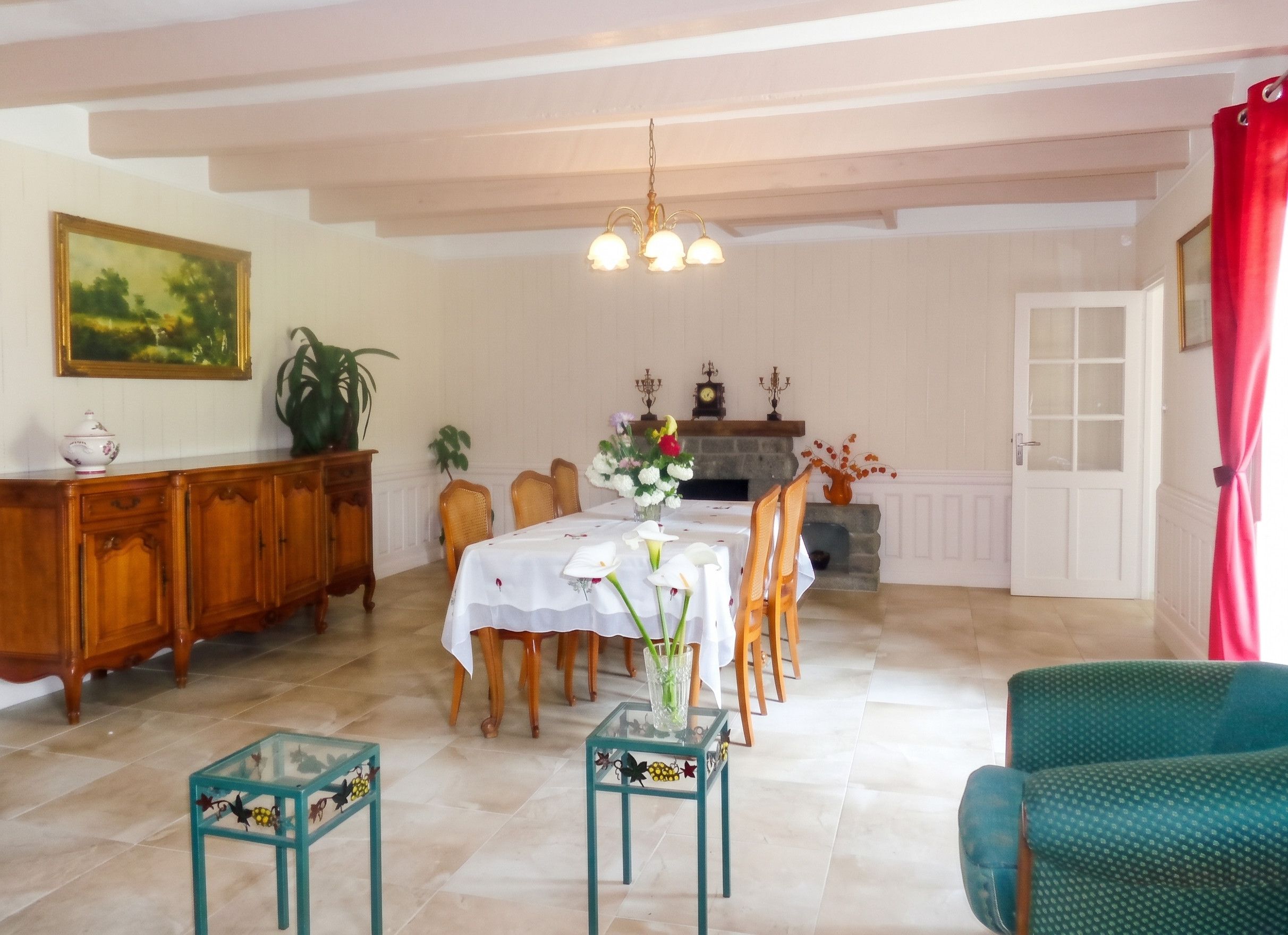 Un coin repas avec une table dressée pour quatre personnes, entourée de chaises, d’un meuble en bois et d’une plante en pot.