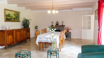 Un coin repas avec une table dressée pour quatre personnes, entourée de chaises, d’un meuble en bois et d’une plante en pot.