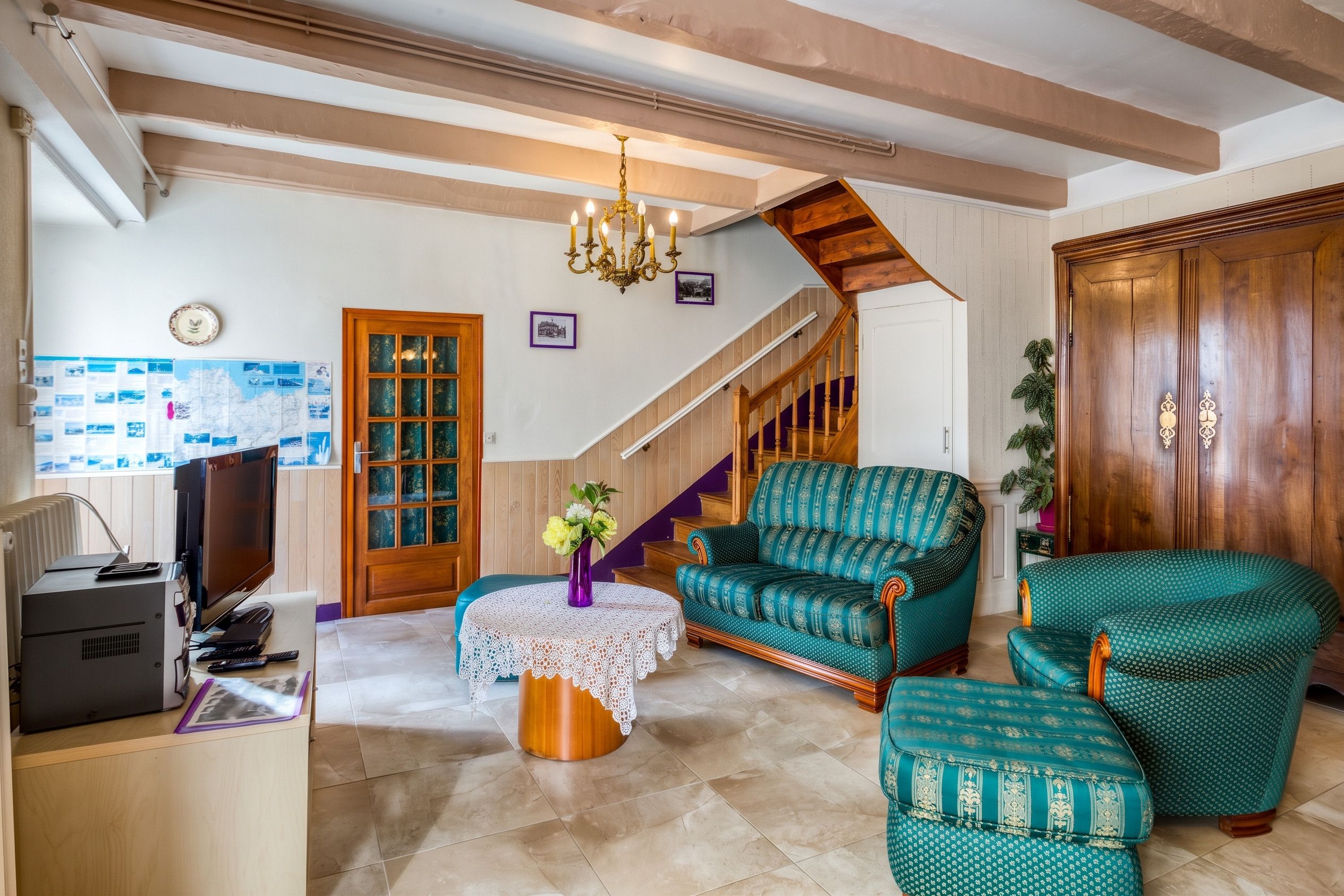 A living room with a wooden staircase, a television, and patterned furniture.