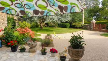 A garden patio with potted plants, a stone floor, and a decorative umbrella.