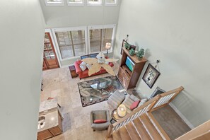 A spacious living area with a glass-top coffee table, a red sofa, and a striped ottoman.