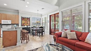 A spacious living area with a red sofa, a glass coffee table, and a kitchen with wooden cabinets and a microwave.