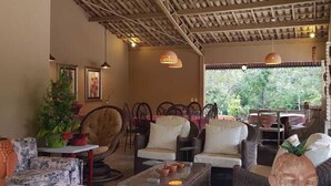 Un'accogliente area relax con mobili in vimini, un soffitto con decorazioni in legno e vista sul verde circostante.