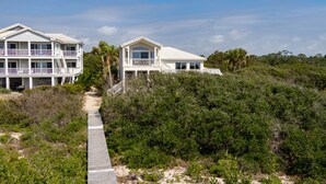 A beachfront property with a wooden boardwalk leading to a two-story building with balconies. - BEACHFRONT Beauty in the Dunes!!, 5BR/4BA, (St. George Island)