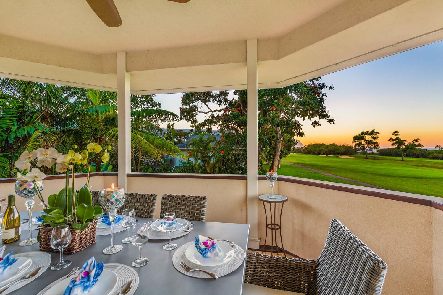 Comedor con una mesa dispuesta para cuatro, con vistas a un campo de golf al atardecer.