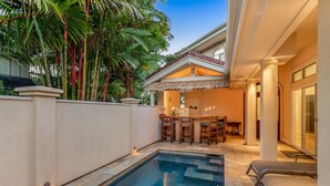 A swimming pool with a bar area, outdoor seating, and a covered patio. - Ohana Kamalani: Lavish Fairwayfront Home w/Pool, AC & Stunning Sunsets! (Princeville)
