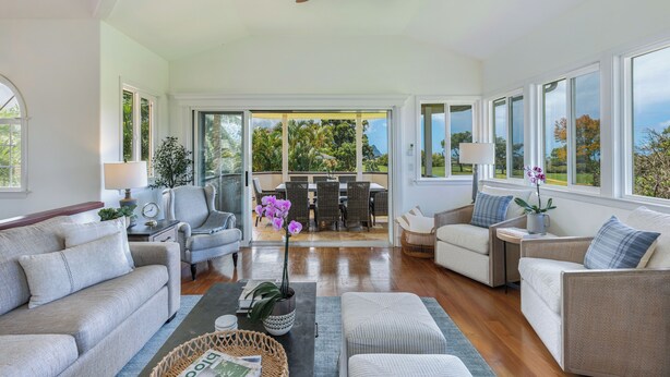 A spacious living room with a large dining area, a ceiling fan, and a view of the outdoors. - Ohana Kamalani: Lavish Fairwayfront Home w/Pool, AC & Stunning Sunsets! (Princeville)