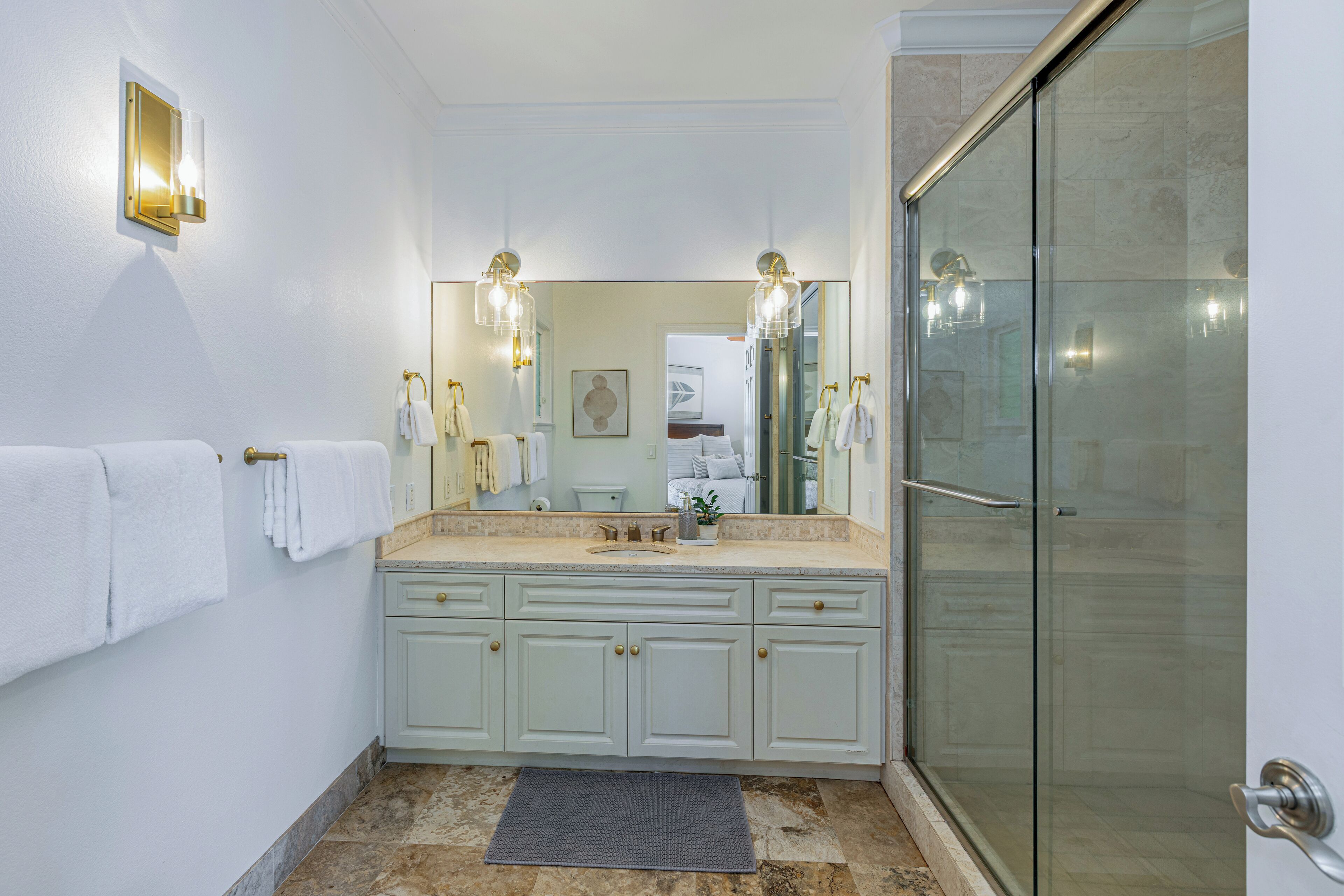 Un baño con un espejo grande, un lavabo con tocador, una zona de ducha y un perchero para toallas.