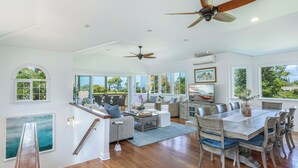 A spacious living area with a dining table, multiple chairs, sofas, and ceiling fans. - Ohana Kamalani: Lavish Fairwayfront Home w/Pool, AC & Stunning Sunsets! (Princeville)