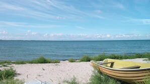Een strand met een gele boot in het zand, een heldere lucht en een verre brug.