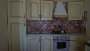 A kitchen with light-colored cabinets, a stove, an oven, and a tiled backsplash. - Vacation home with sea view, Budoni - Sardinia  (Solitá)