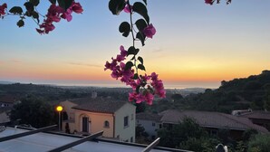 A rooftop with a view of a sunset, a building with a tiled roof, and a street lamp. - Vacation home with sea view, Budoni - Sardinia  (Solitá)