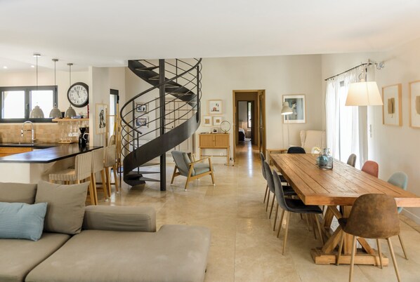 Un amplio salón con una escalera en espiral, una mesa de comedor y una zona de estar acogedora.