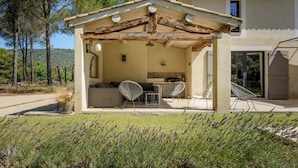 A covered outdoor seating area with a dining table, chairs, and a pergola structure. - Bastide Blanche: Villa with swimming pool and pétanque court in Lourmarin. (lourmarin)