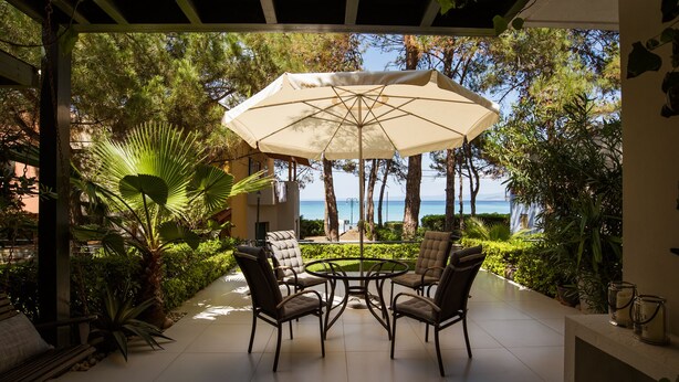 Une terrasse extérieure avec une table ronde et quatre chaises, entourée d’une végétation luxuriante et offrant une vue sur la mer.
