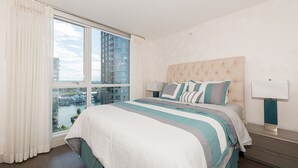 Ein modernes Hotelzimmer mit einem großen Bett, Blick auf die Stadt und einem mit Vorhängen versehenen Fenster.
