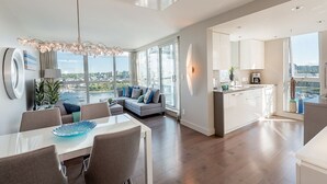 Ein modernes Wohnzimmer mit Essbereich, einer Küche und einem großen Fenster mit Blick auf die Stadt.