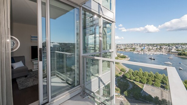 Eine moderne Wohnung mit großen Glasfenstern, einem Balkon und Blick auf einen Hafen sowie die Stadtlandschaft.
