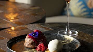 Un plato de postre con un dulce de chocolate, una porción de helado y una copa de martini sobre una mesa de baldosas.