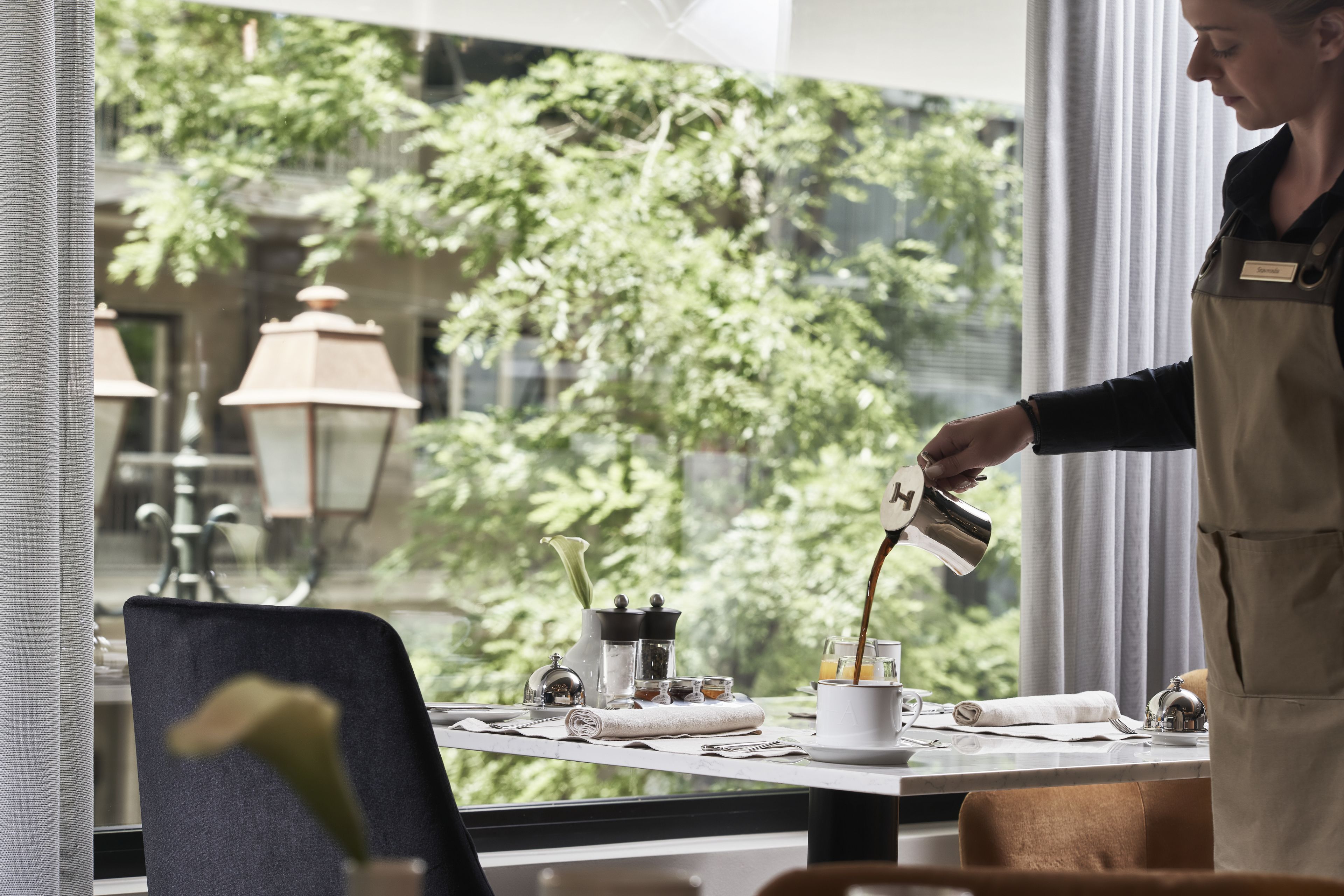 Ett hotellrum med ett stort fönster, en plats för att göra kaffe och utsikt över grönområden utanför.