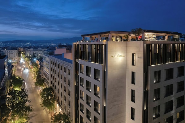 A modern building with a rooftop bar and a sign reading "Academias."